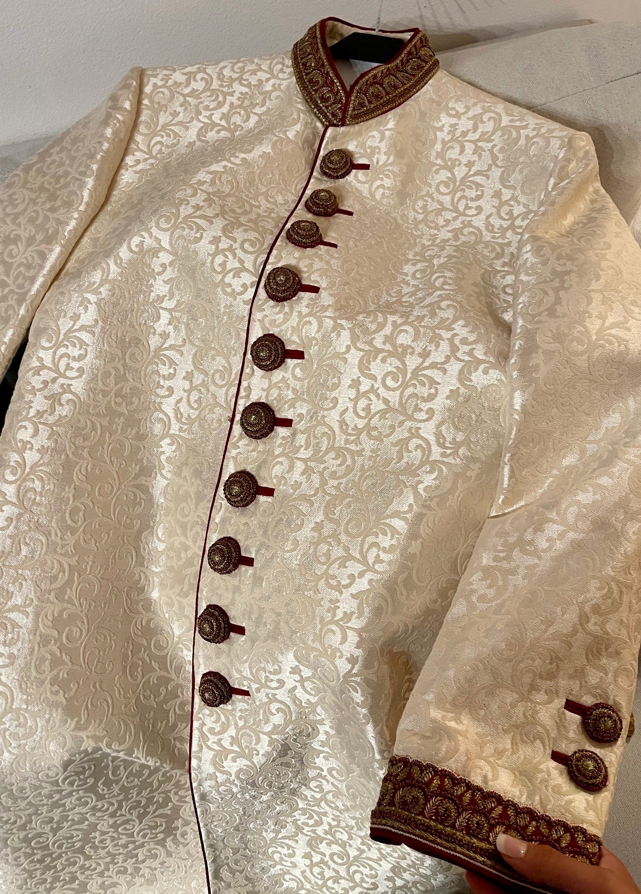 Beige/off-white sherwani embroidered with gold motifs, paired with your own tailored dress pants.