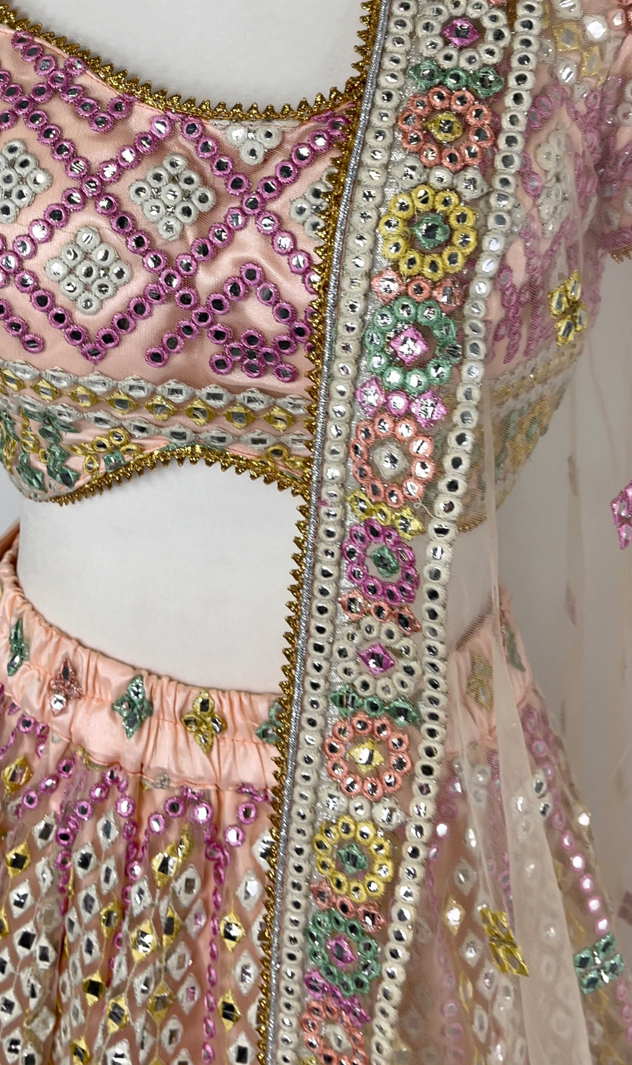 Stunning multi-colored pastel bridal lehenga is covered in beautiful embroidery and mirror work.